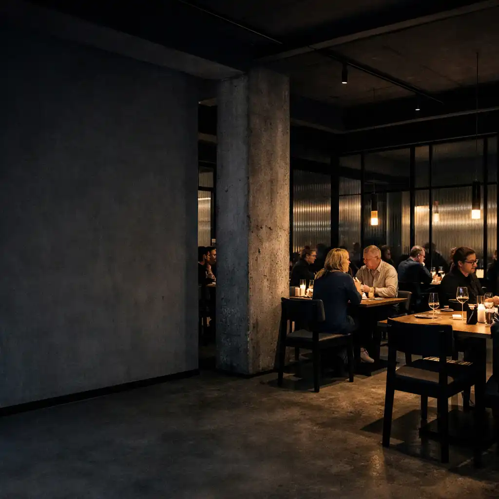 Abendinterieur mit Betonpfeilern, dunklem Holz, geripptem Glas und besetzten Tischen